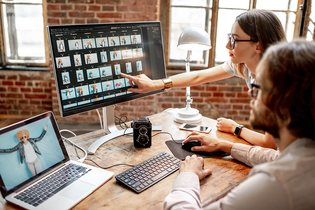 A woman and a man looking intently at an image gallery on a computer screen.